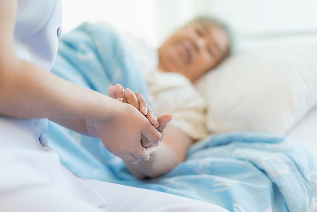 Nurse holding on to the hands of a patient to comfort them