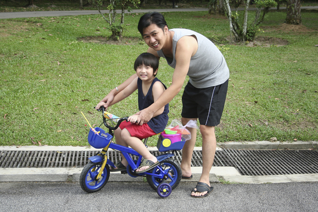 Father teaching his young daughter how to cycle, which is also a form of physical activity or aerobic exercise.