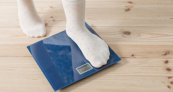 A young teenager stepping on the scale to check her weight