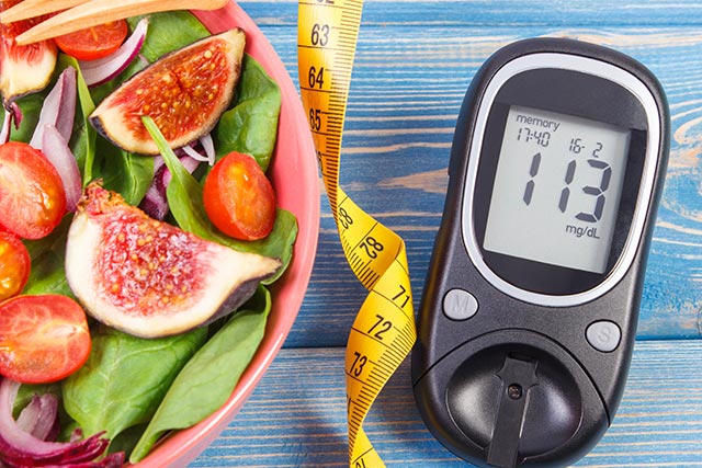 Healthy salad of spinach, figs and cherry tomatoes beside a glucometer