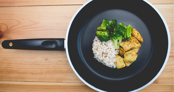 Small portion of rice, brocolli and curried chicken in a pan