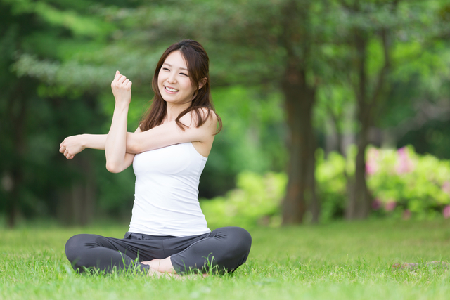 Young woman stretching in a park, getting ready to begin her workout routine