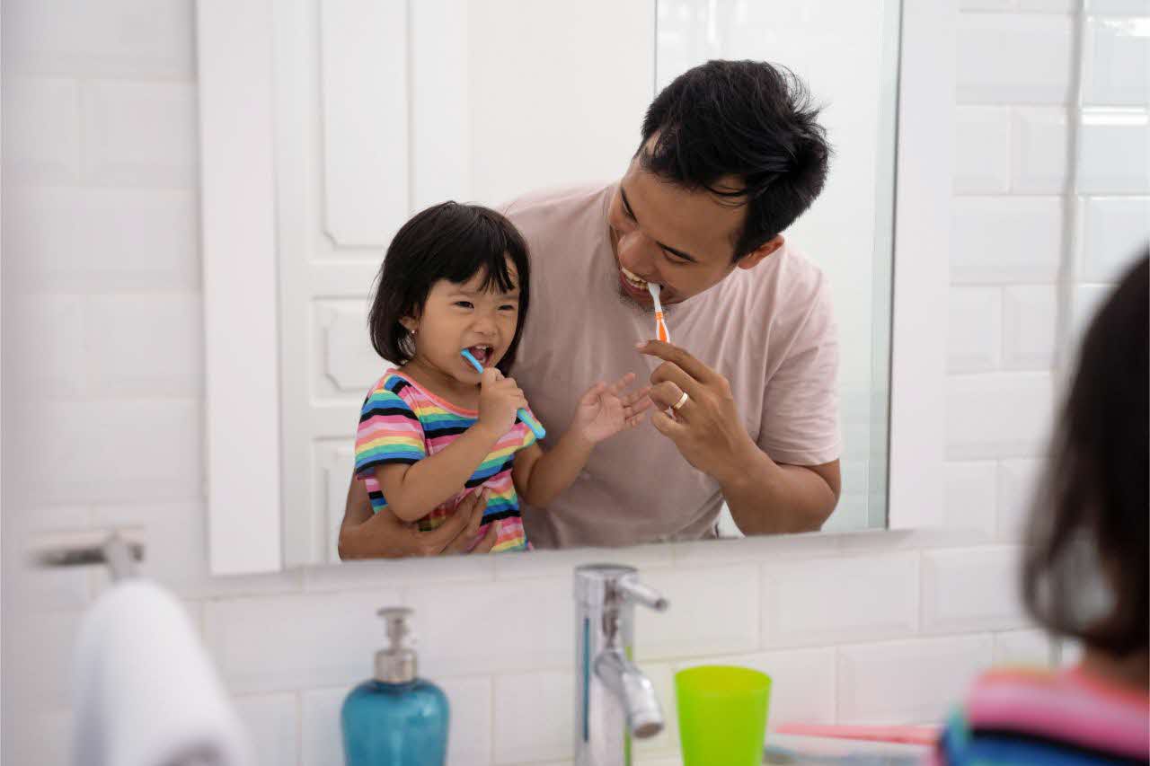 Father and daughter brushing teeth