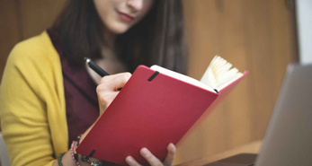 young asian woman penning down her goals in a notebook