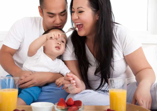 Dad, mom, and one-year-old baby eating healthily together