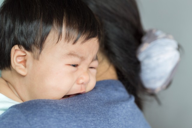 crying toddler on his mum's shoulders