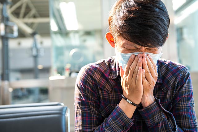 Asian man feeling unwell and is wearing a mask