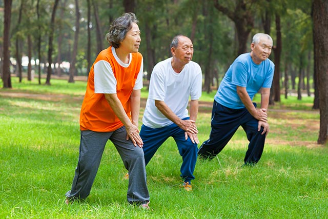 Older people exercising in groups outdoors.