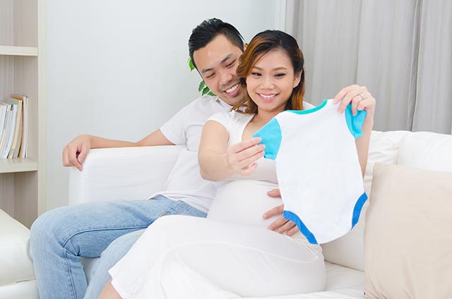 Asian couple looking at baby clothes