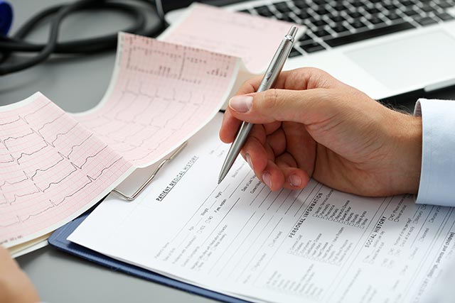 Doctor examining a cardiogram and filling up a chart