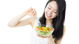 A woman eating a salad for to maintain a healthy weight and lower her cholesterol level. 