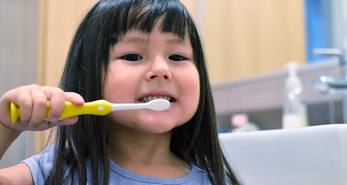 A young girl is brushing her teeth