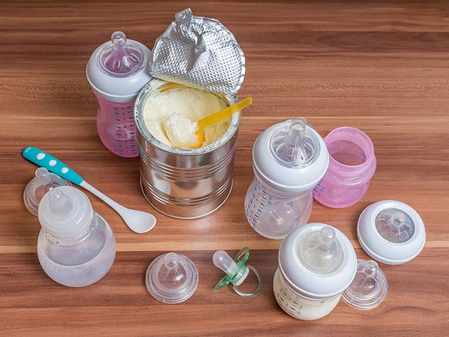 Can of milk powder surrounded by baby milk bottles