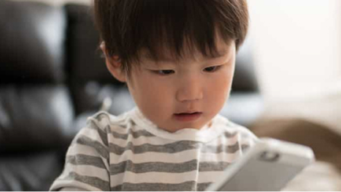 Child holding and looking at a smartphone.