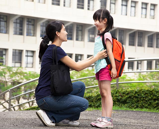 mother adjusts the bag straps for her daughter so she can have the right posture