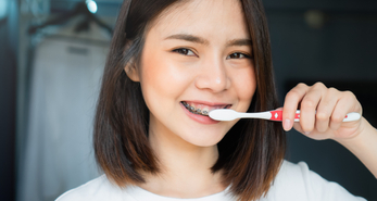 woman with braces maintaining good oral hygiene by brushing her teeth