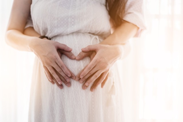 husband and wife hands on pregnant belly