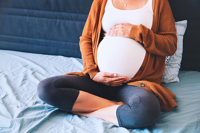 Pregnant woman sitting on the bed