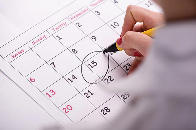 A woman circling a date on a calendar