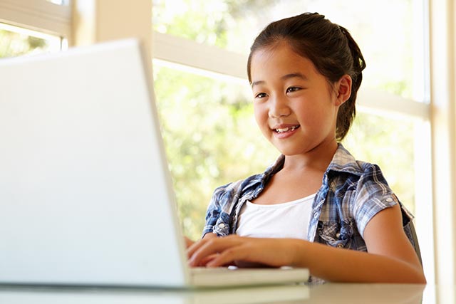 young asian girl sitting up straight while using a laptop
