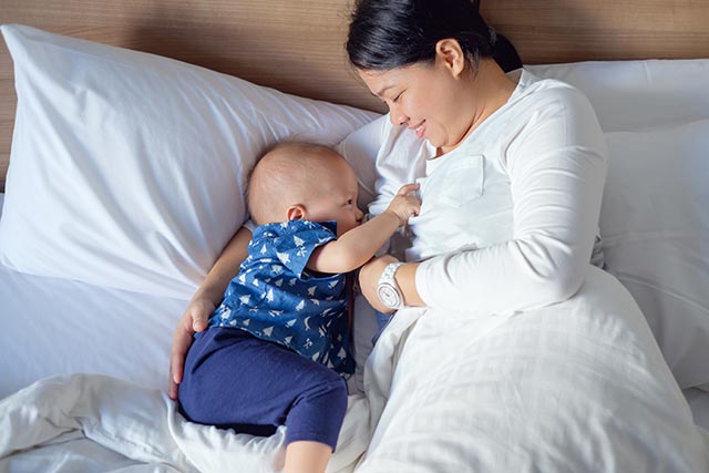 Mother breast feeding her new born baby in bed