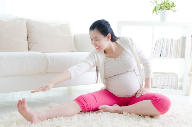 happy pregnant asian woman stretching