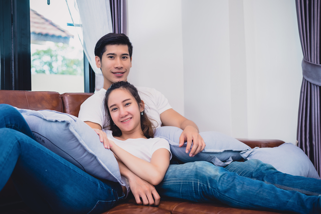 Happy asian couple cuddling and relaxing on the sofa