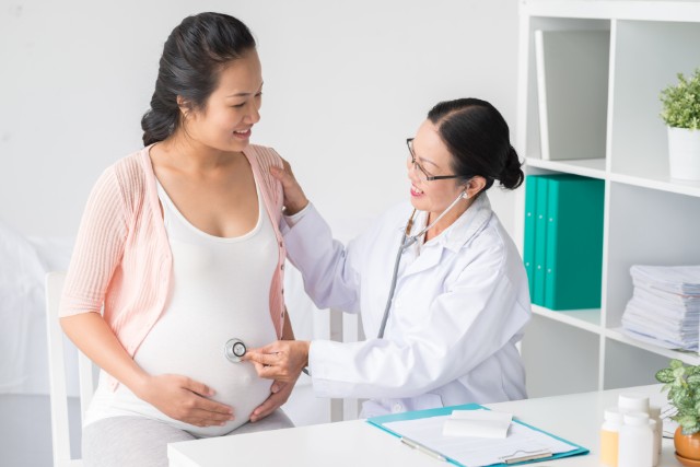 female doctor examining her pregnant patient's belly