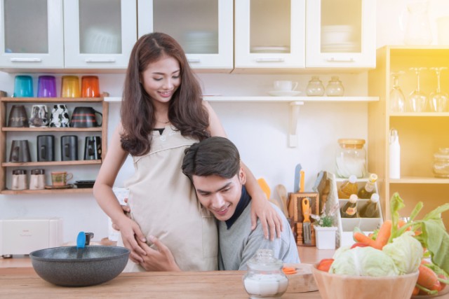husband helping his pregnant wife in the kitchen