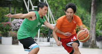 Two teenage boys having a one-on-one match while playing basketball.