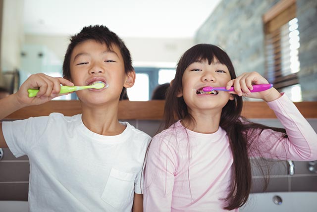 Brother and sister having a friendly competition while brushing their teeth