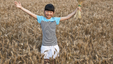 a young kid standing in a field of wheat