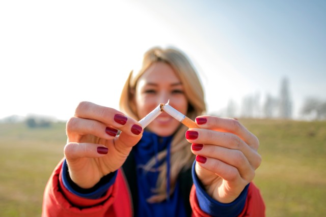 Woman holding two cigarettes together.