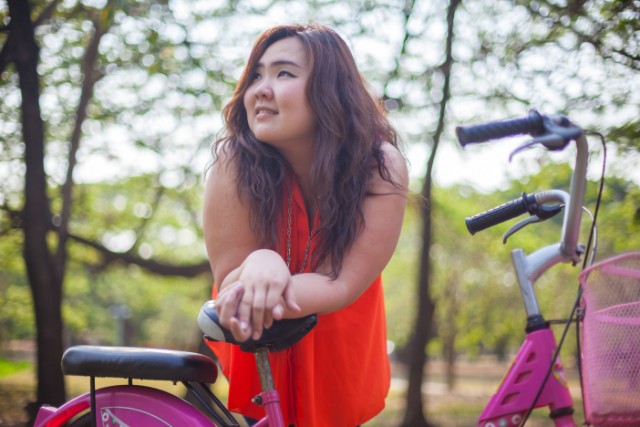 Young woman leaning on a bicycle.