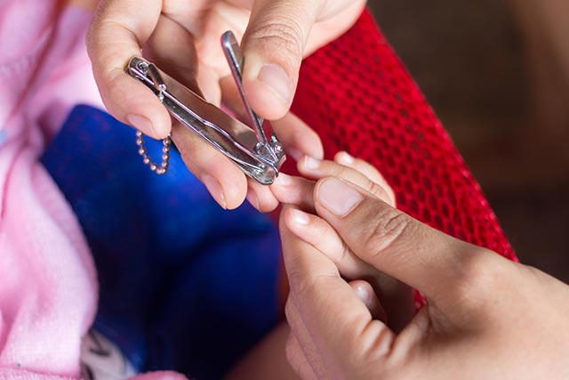 Asian mother cutting the nails for her baby