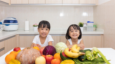 happy-asian-chinese-little-sisters-with-fruit-and-vegetable-in-the-kitchen-at-home.jpg