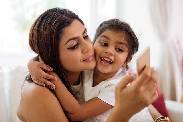 Mother distracted by phone while playing with her daughter