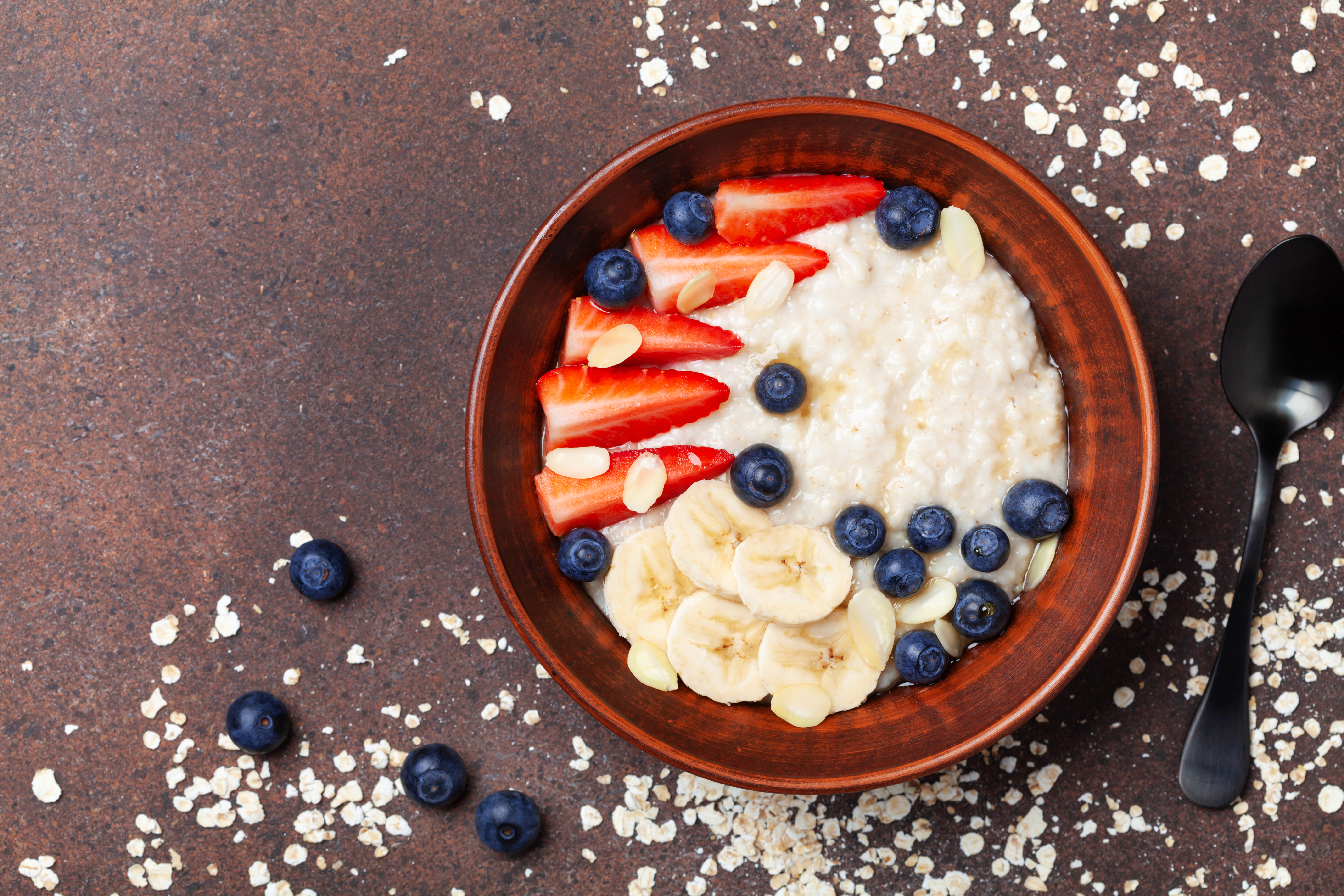 A bowl of oatmeal with low-fat milk, bananas, strawberries and blueberries