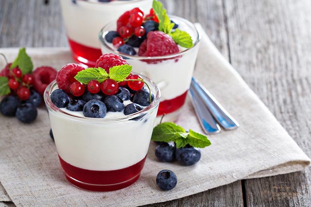 Fresh fruit yoghurt parfait in a clear glass toppied withblueberries and raspberries