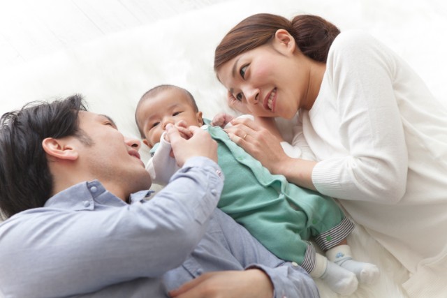 two asian parents play with their baby