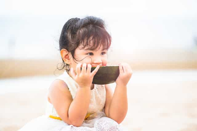 A young girl having some watermelon instead of fruit juice as part of her nutritional needs.