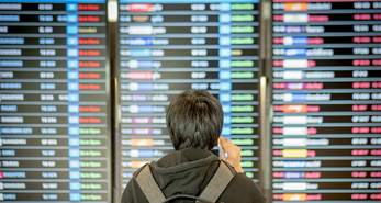 Man checking the departure board in the airport for his flight