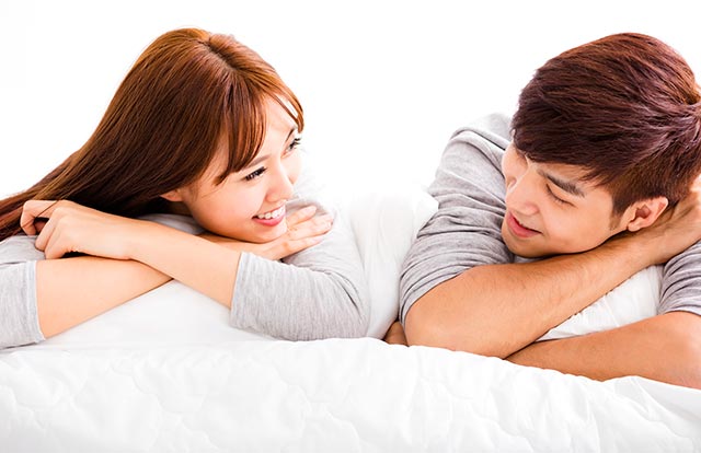 Young asian couple cuddling in bed