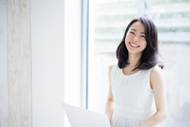Happy asian woman with laptop smiling at the camera