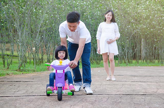 Walking in the park is a great exercise for this pregnant woman, who is with her husband and child.
