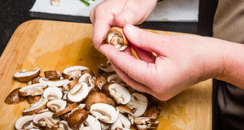 Hands using knife to cut healthy mushrooms