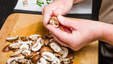 Hands using knife to cut healthy mushrooms