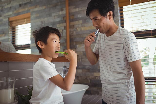 Father and son brushing their teeth together