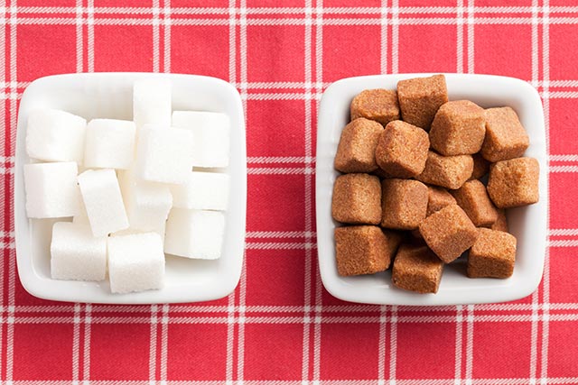 Bowls of brown and white sugar placed on a red checkered table