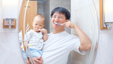 Asian fathers brushing teetch with his son in arms